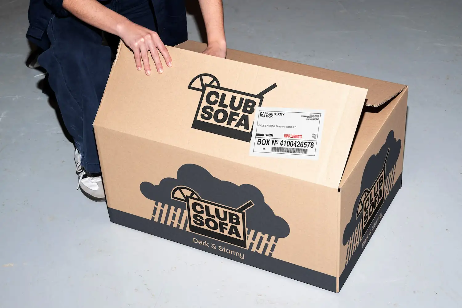 Een afbeelding van een doos met Club Sofa-branding. De doos wordt geopend en zegt 'Dark & Stormy'.