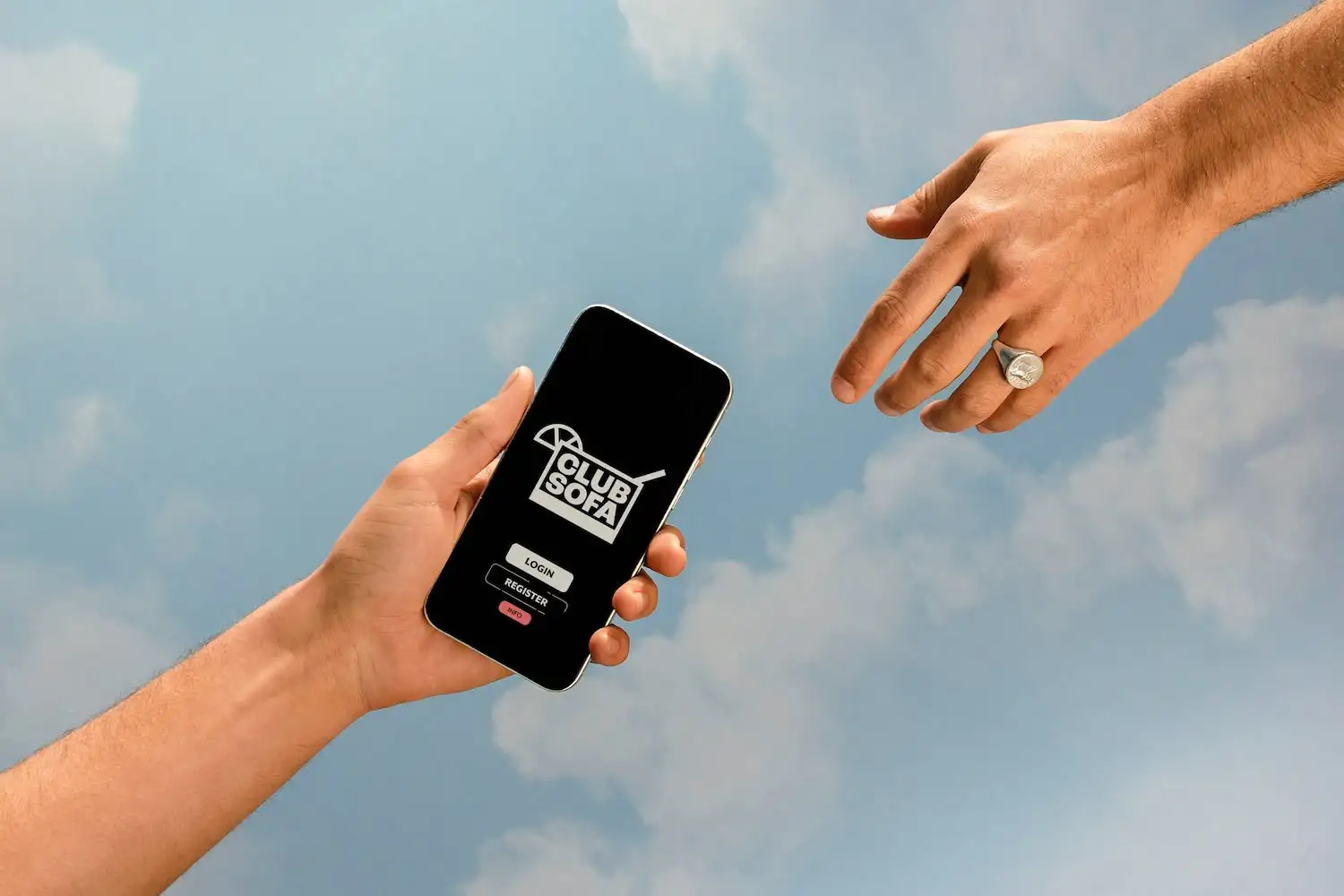 Hand die een smartphone vasthoudt met het inlogscherm van Club Sofa open. Een andere hand reikt ernaar en imiteert het beroemde schilderij 'De schepping van Adam' van Michelangelo.