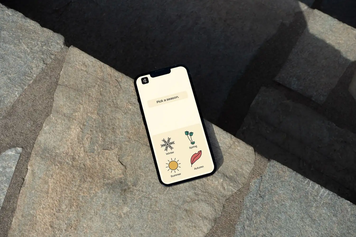 Smartphone die de Club Sofa-app toont. Er staat 'Kies een seizoen' met vier illustraties als opties.